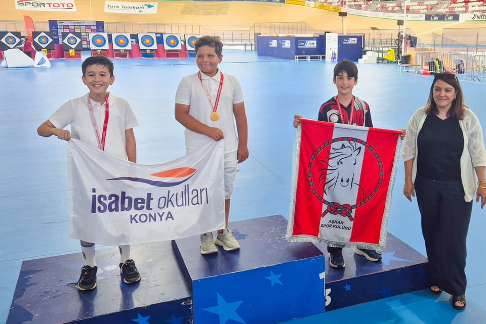 Kürsüde madalyalı erkek sporcular, Aşkar bayrağı ve okul bayrağıyla