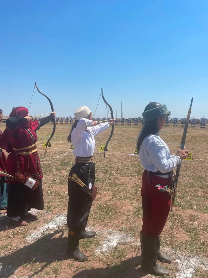 Geleneksel kıyafetli okçular açık arazide geleneksel yaylarla atış yapıyor