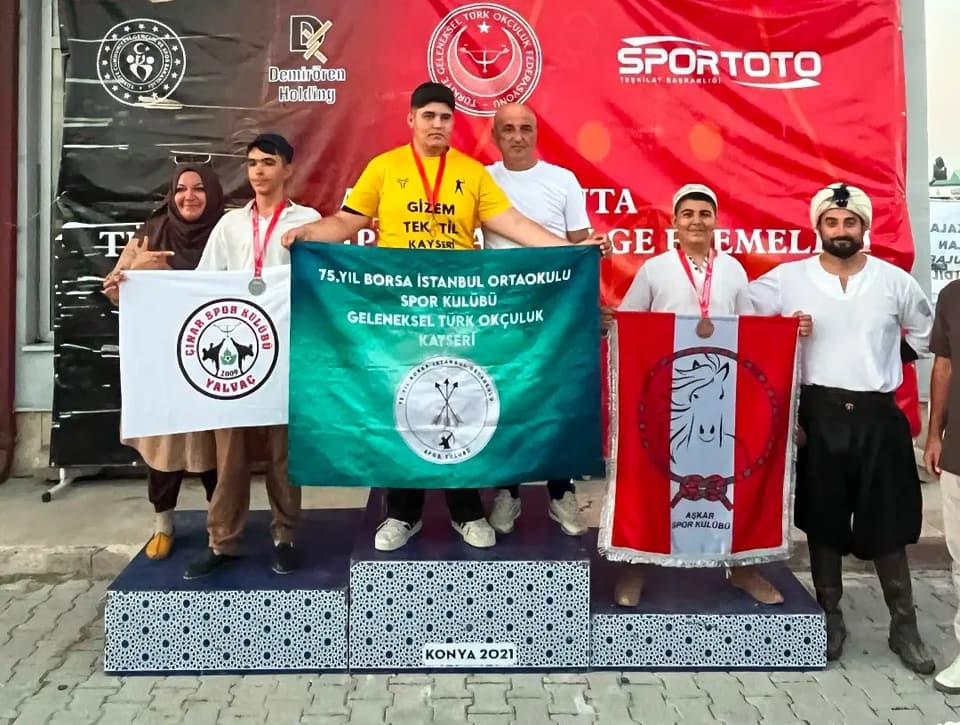 Geleneksel okçuluk kürsüsü; kulüp bayraklarıyla madalyalı sporcular