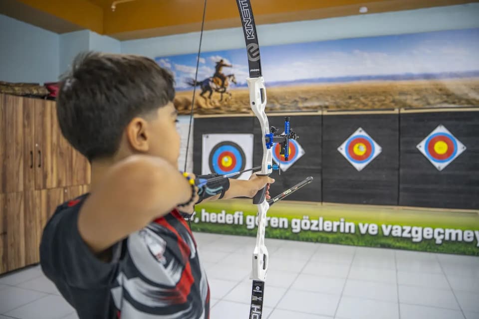 Çocuk sporcu salonda beyaz olimpik yayla nişan alıyor